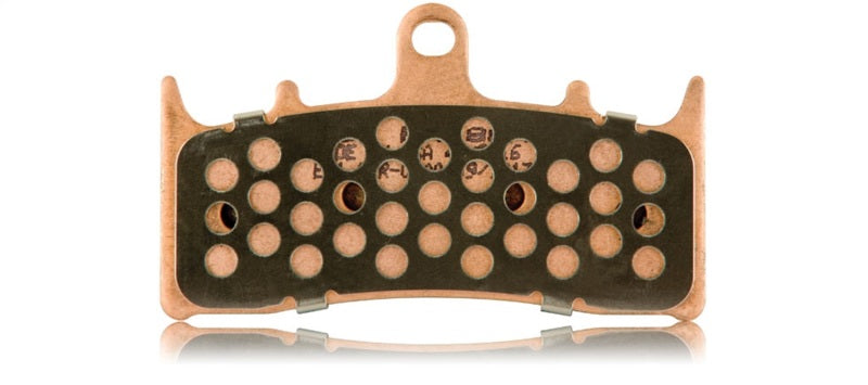 Close-up of EBC sintered brake pad backside showing copper backing plate, perforated friction compound, and stamped markings